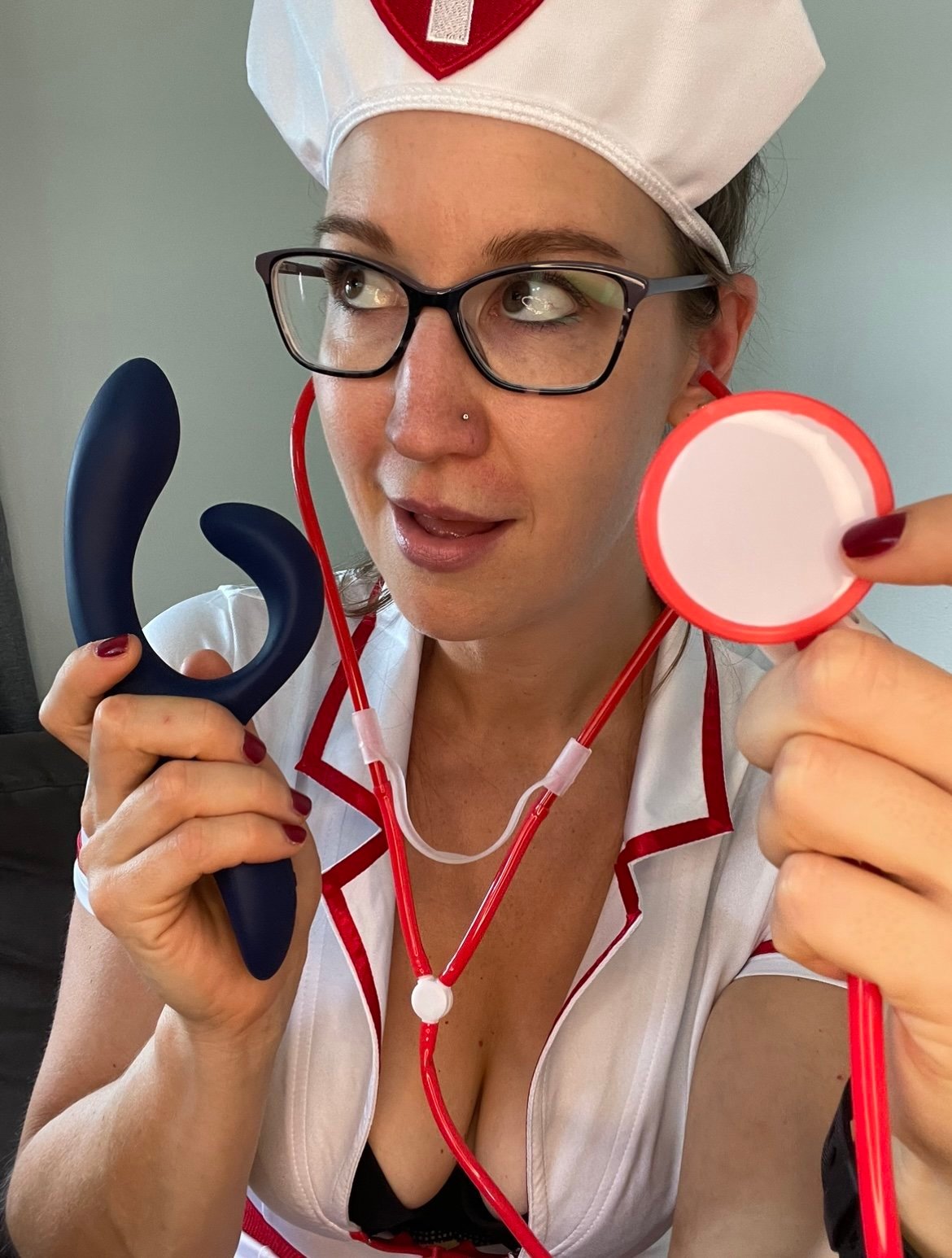 Pleasure Toy Queen Patricia holding the W-vibe Nova 2 vibrator and wearing a nurse costume