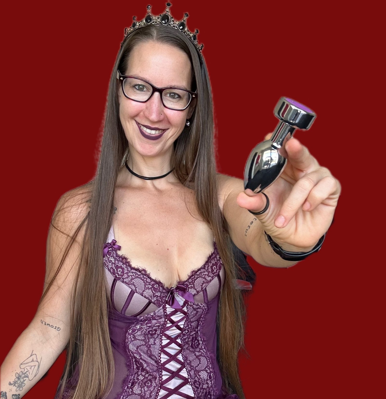 Pleasure Toy Queen Patricia holding a steel vibrator butt plug