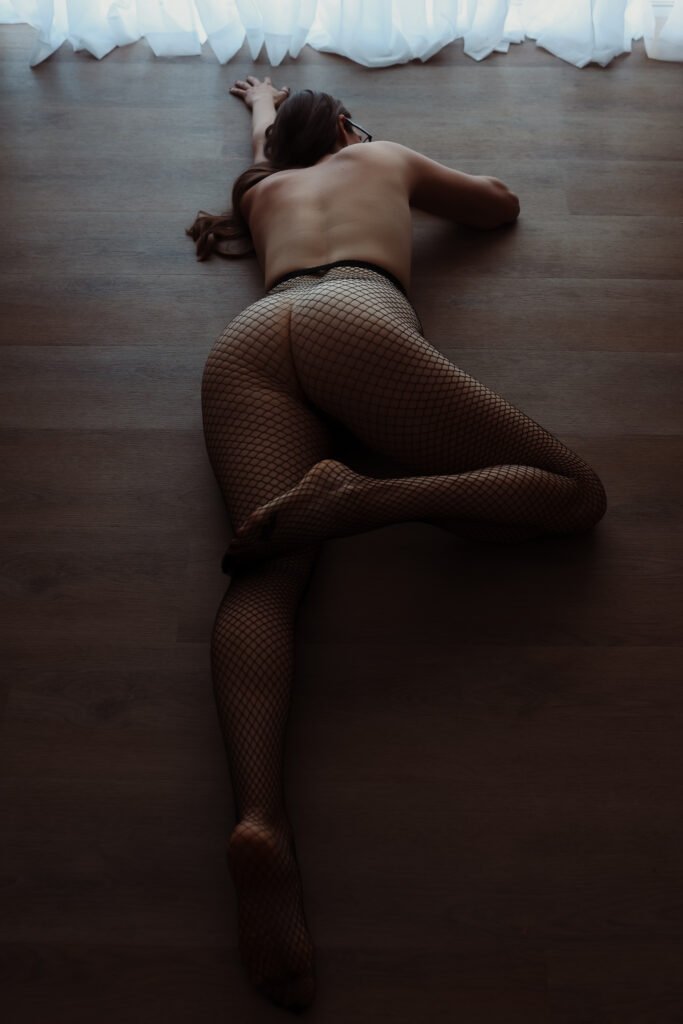 The Pleasure Toy Queen laying on the floor with her fishnet stockings.